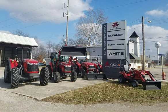 Close-up of the E.J. Kehrer Farm Supply lot showing a lineup of Massey Ferguson tractors beside the dealership sign.